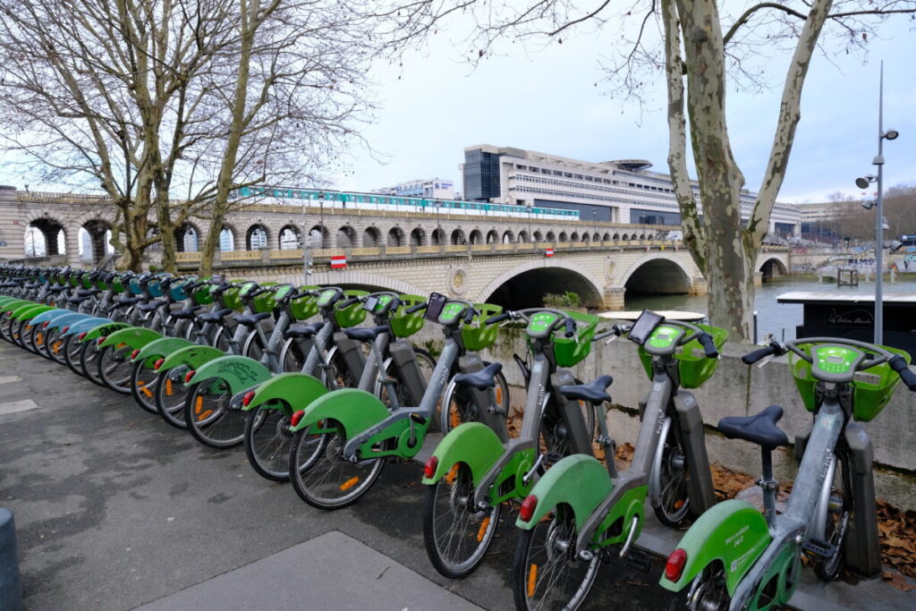 Bercy bridge in Paris with a moving metro train and a Velib bike station in the foreground.