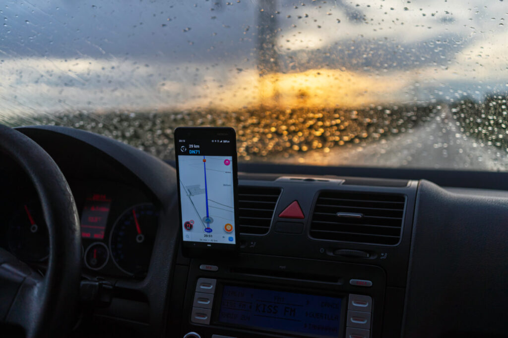 Person driving and accessing the Waze maps application on their smartphone for navigation.